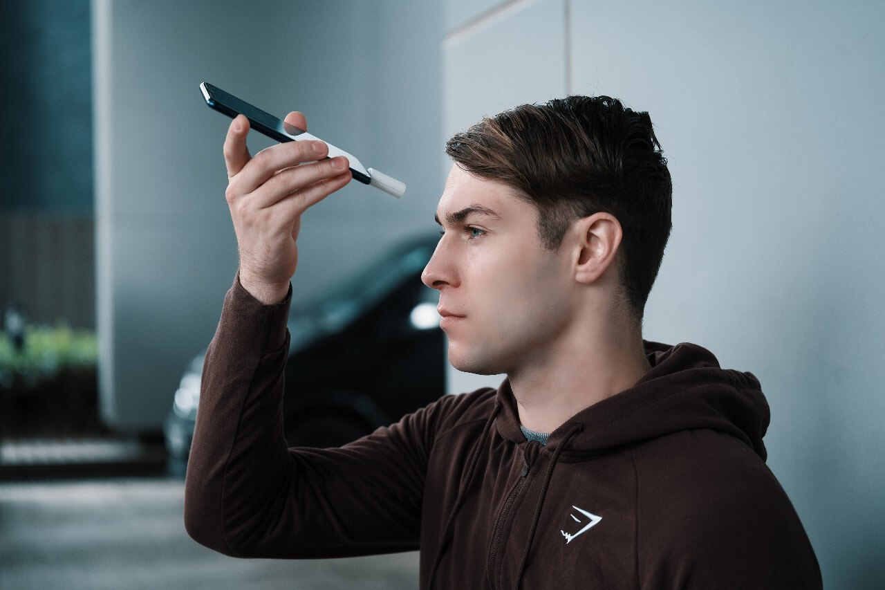 A man takes a temperature reading of his forehead with a smartphone, equipped with a thermometer.